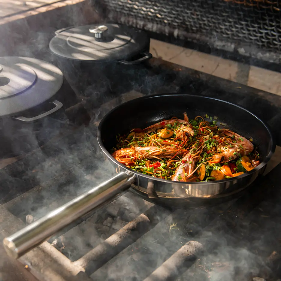 Roestvrijstalen Ceramic High Fry 28cm pan met een gerecht van garnalen en groenten op een rokerige barbecue.